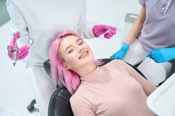 Uśmiechnięta Kobieta Różowymi Włosami Personelem Medycznym Znajduje Się Gabinecie Stomatologicznym — Zdjęcie stockowe