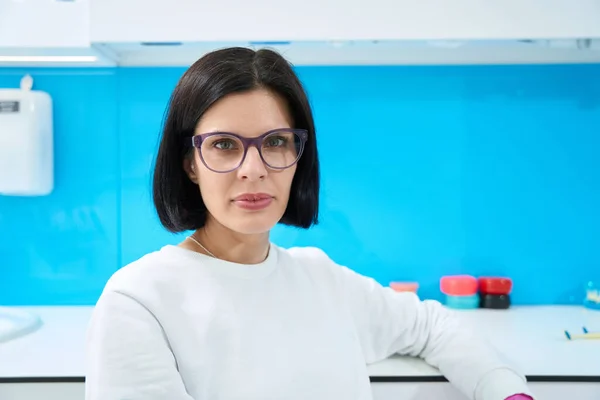Woman doctor at the workplace in a medical facility, she is in a white uniform and glasses
