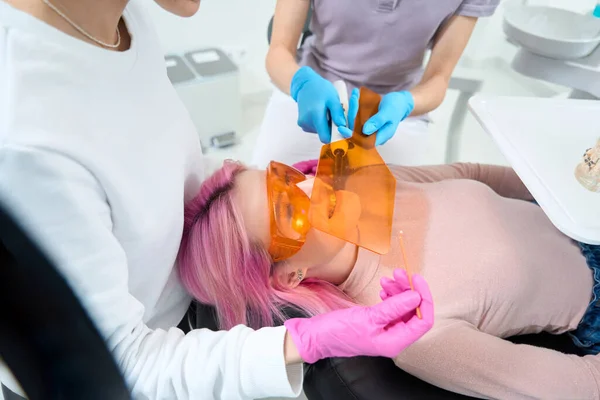 Pembe Saçlı Koruyucu Gözlüklü Kadın Hasta Diş Sandalyesinde Yatıyor Doktor — Stok fotoğraf
