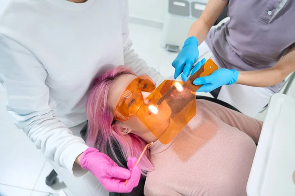 Koruyucu Gözlüklü Kadın Hasta Diş Sandalyesinde Yatıyor Doktor Bir Asistanla — Stok fotoğraf