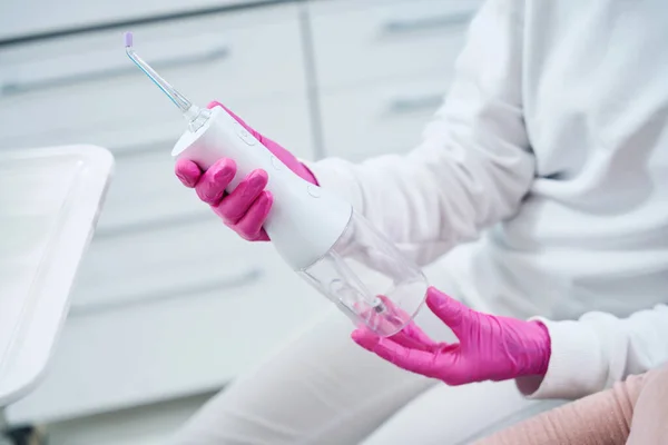 Dentysta Różowych Rękawiczkach Trzyma Nawadniacz Rękach Nowoczesne Narzędzie Pielęgnacji Jamy — Zdjęcie stockowe