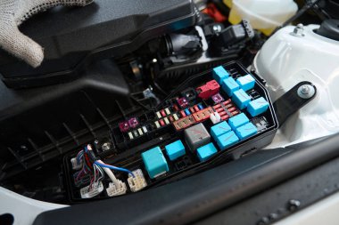 Lastik dükkanında teknik inceleme sırasında koruyucu eldivenli bir erkek arabanın çakmağını kontrol ediyor.