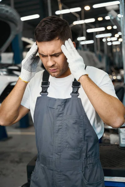 Portret Mężczyzny Ubraniach Ochronnych Rękawiczkach Stojącego Garażu Trzymającego Głowę Zmęczeniu — Zdjęcie stockowe