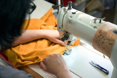 Dikiş makinesine yazı yazan kadın gözlüklerle çalışıyor.