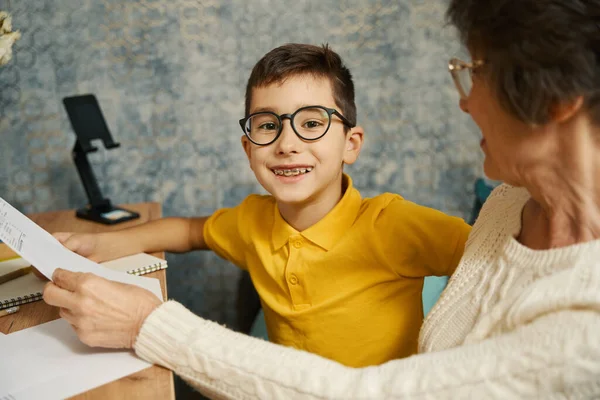 Sonriente Niño Con Gafas Aparatos Ortopédicos Sentado Mesa Con Abuela —  Fotos de Stock