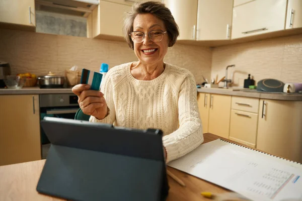 Γριά Γυναίκα Γυαλιά Που Κάθεται Στο Τραπέζι Tablet Κρατώντας Πιστωτική — Φωτογραφία Αρχείου