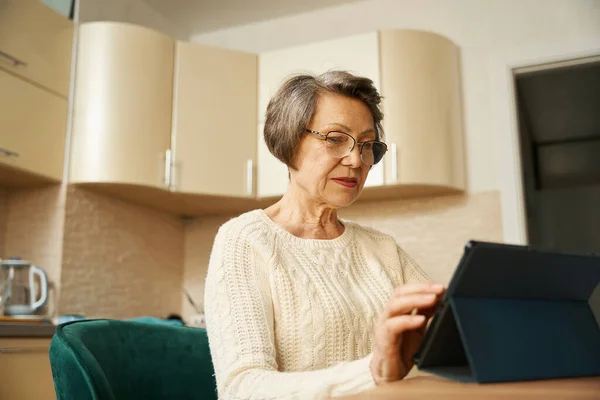 Γριά Γυναίκα Γυαλιά Κάθεται Στο Τραπέζι Κρατώντας Tablet Και Ψώνια — Φωτογραφία Αρχείου