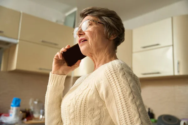 Γριά Γυναίκα Γυαλιά Στέκεται Στην Κουζίνα Κρατώντας Smartphone Και Έχοντας — Φωτογραφία Αρχείου
