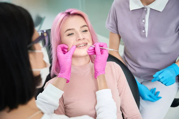 Młoda Różowłosa Kobieta Spotkaniu Ortodontą Jest Serwisowana Przez Aparat Zęby — Zdjęcie stockowe