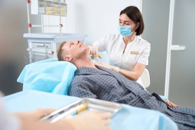 Deri yenilenmesi için hastasına iğne yaparken plazmalı şırınga kullanan yetenekli bir kadın doktor.