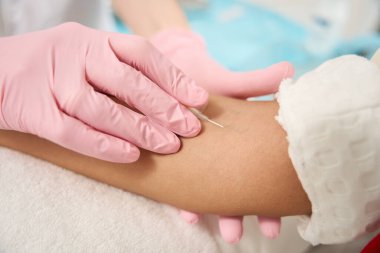 Doktorun koruyucu eldivenleriyle damara iğne yaparken çekilmiş bir fotoğrafı.