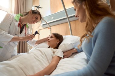 Doktor elinde hasta kulak kanalını incelemek için bir otoskop tutuyor.