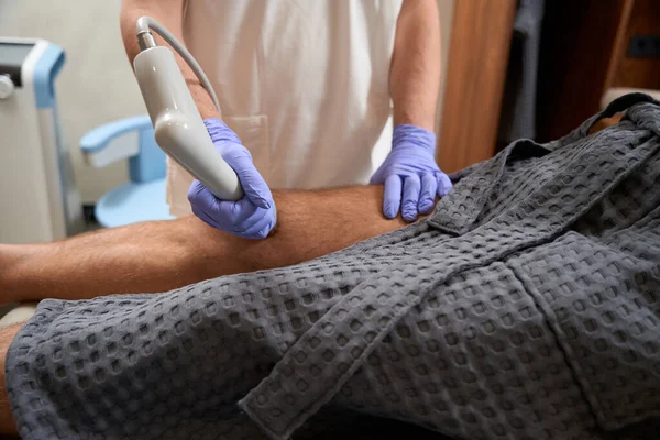 Cropped photo of medical staff using shockwave therapy for helping patient live with less pain