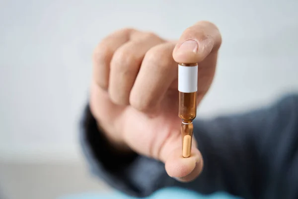 Man holds an ampoule with medicine in his hand, this is a modern drug for plasma therapy