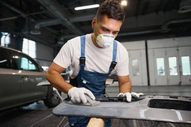 Lastik montajına başlamadan önce koruyucu eldivenli ve takım elbiseli tamirci öğütme aletini ve temizlik yüzeyini tutuyor.