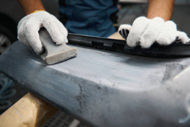 Koruyucu eldivenli bir erkek lastik montajına başlamadan önce dişlerini gıcırdatıyor ve temizlik yapıyor.