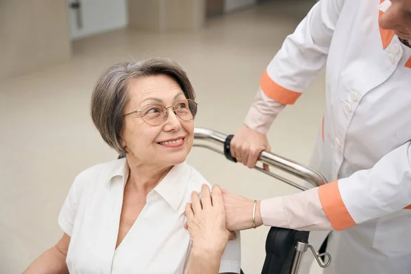 Woman with a disability moves in a wheelchair, she is helped by a caring nurse
