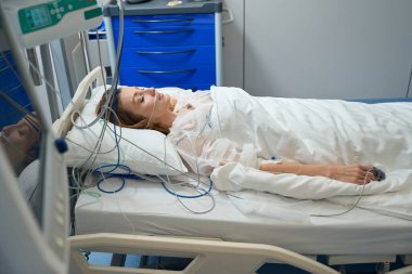 Beautiful lady lying on bed in ward and sleeping, connected to oxygen supply in private clinic