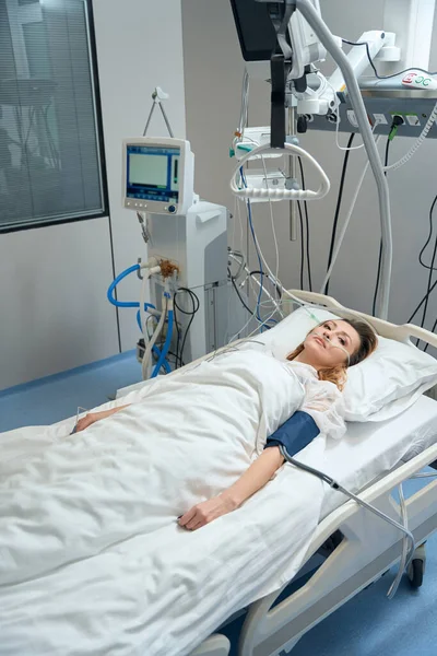 Female lying on bed in ward, connected to oxygen supply in private clinic