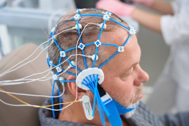 Patient undergoing an EEG encephalography diagnostic procedure, he is undergoing a check-up at a medical center