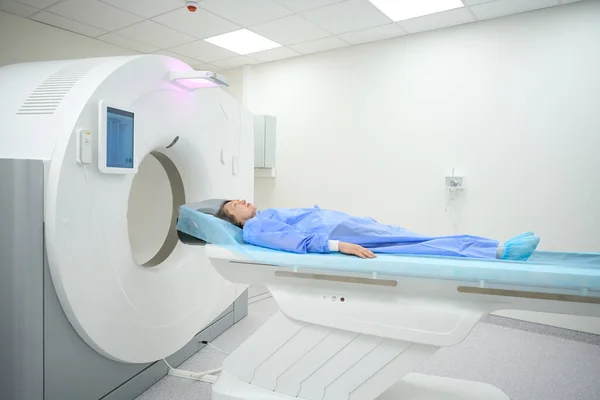 Woman lies on a special mobile surface of the MRI machine, she is in the diagnostic department of the hospital
