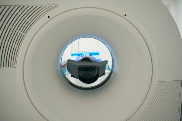 Patient is placed in the chamber of a modern MRI machine, she is being diagnosed in a medical clinic