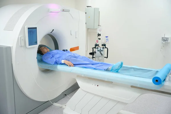 Patient undergoes an MRI diagnostic procedure using modern equipment, she lies on a special mobile surface