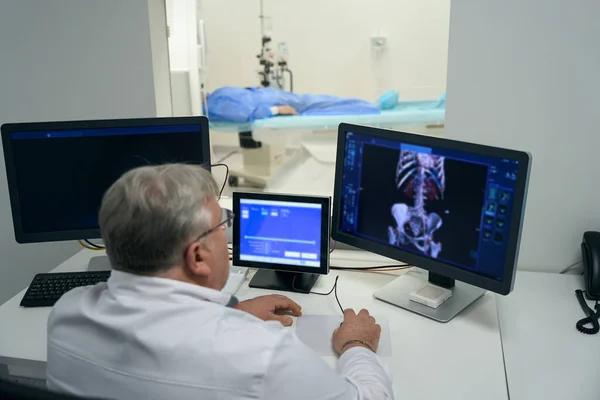 Male Diagnostician Performs Scan Using Modern Equipment Patient Skeleton Visible — Stok fotoğraf