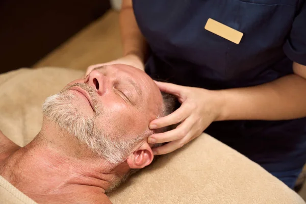 Patient receives a wellness relaxing massage, a clinic worker massages his head