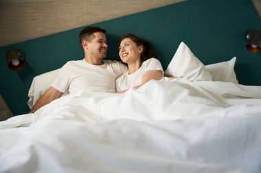 Newlyweds spend the morning together in bed, they settled down comfortably