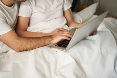 Young woman and her friend spend the morning together in bed, they use a laptop