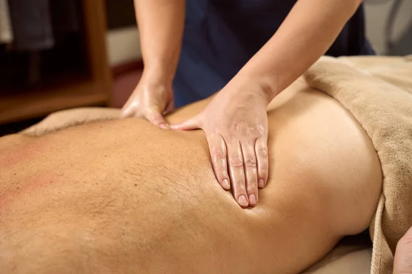 Patient lies on his stomach, he is given a back massage, the masseuse gently kneads his muscles