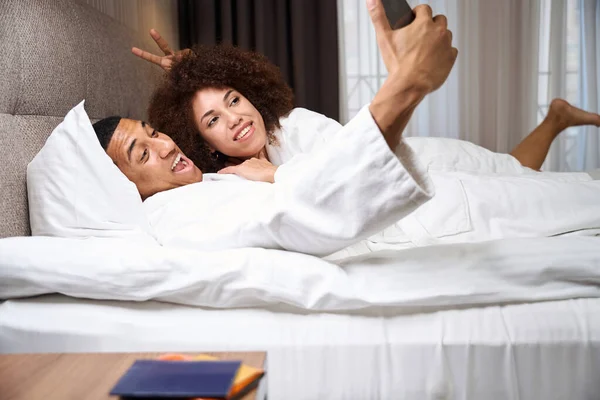 Traveling Couple Takes Comic Selfie Bed Hotel Room Next Bedside — Stock Photo, Image