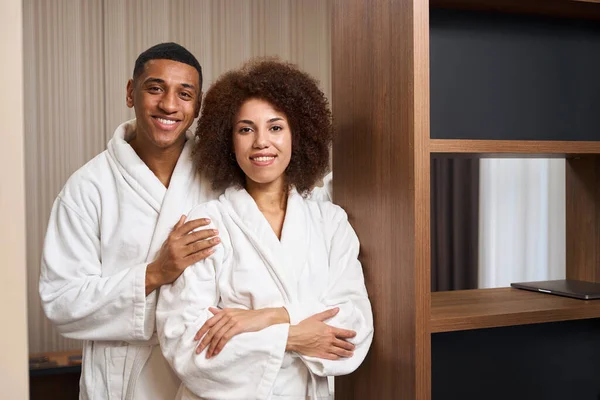 Multiracial Happy Couple Standing Cozy Bathrobes Hotel Room Minimalistic Design — Stock Photo, Image
