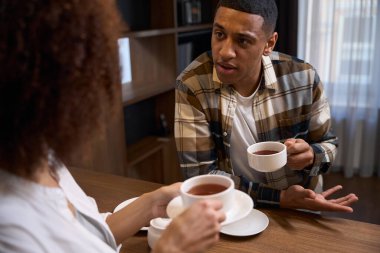 Young spouses are talking over morning tea in a hotel room, the room has a minimalist interior