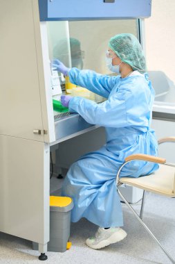 Female scientist working while holding special pipette in laboratory