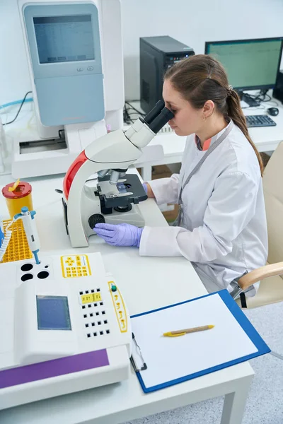 Hematologist Examines Biomaterial Sample Microscope Woman Protective Gloves Overalls — Stock Photo, Image