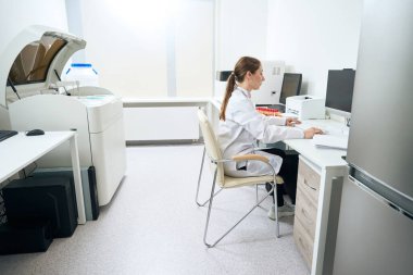 Woman scientist at the workplace in the diagnostic laboratory in the testing unit, modern equipment in the office