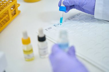 Llaboratory assistant drops a blue reagent from a pipette onto an indicator palette, a specialist determines the blood group