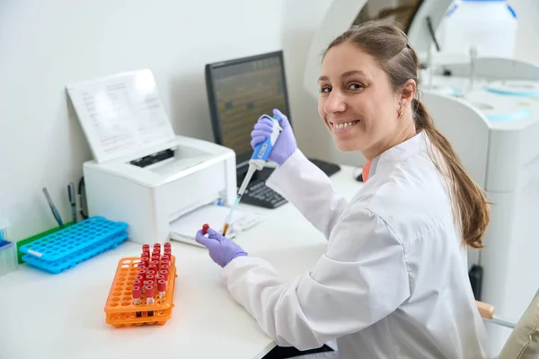 Uśmiechnięty Pracownik Laboratorium Jej Miejscu Pracy Pracuje Próbkami Krwi Probówki — Zdjęcie stockowe