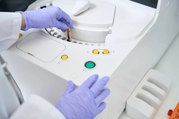 实验室助理将带有血样的试管放入免疫化学发光分析仪 这是一种现代诊断仪器 — 图库照片