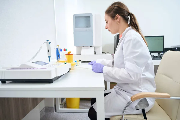 在血科医生的工作场所 一名妇女被用于血液检测的特殊设备围绕着 在一个现代化的实验室工作 — 图库照片