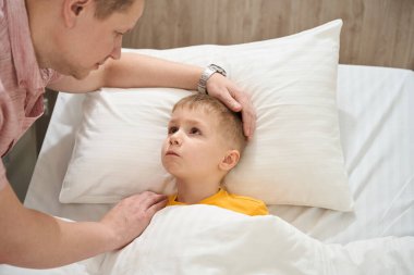 Depresyondaki küçük çocuğun yakın plan portresi hasta odasında babasına bakarken tıp yatağında yatıyor.