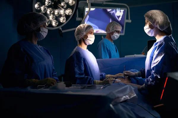 麻酔下の患者は手術台の上にあり 手術チームによって運営されています — ストック写真