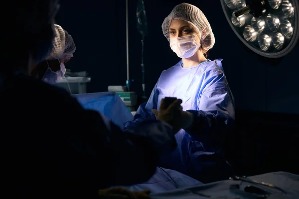 Female Stands Surgical Table Operating Room She Passes Instrument Her — Stock Photo, Image