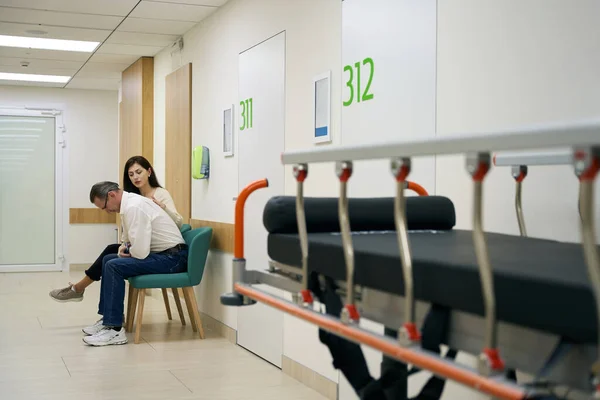 Kobieta Pociesza Mężczyznę Szpitalnym Korytarzu Pierwszym Planie Jest Łóżko Mobilne — Zdjęcie stockowe