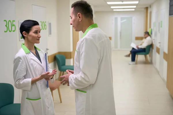 Kadın Sağlık Çalışanı Hastane Koridorunda Arkadaşıyla Iletişim Kuruyor Kadının Elinde — Stok fotoğraf