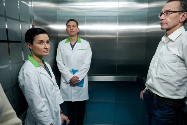 Люди Медицинских Халатах Едут Больничном Лифте Рядом Стоит Человек Повседневной — стоковое фото