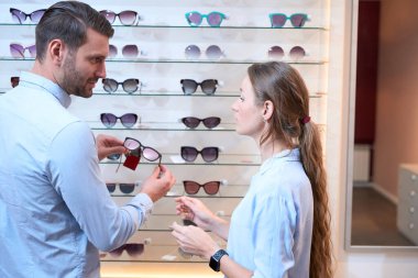 Yakışıklı beyaz adam ve zarif kadının arka plan portresi lüks mağazadaki bardakları tartışıyor.