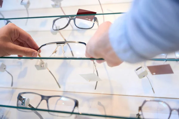 不明身份者的低角度肖像画是在光学商店里选用时髦的眼镜片作为礼物 — 图库照片